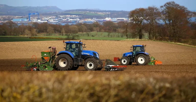Tractor pulling a seed drill to sow seeds in neat rows across a farm field