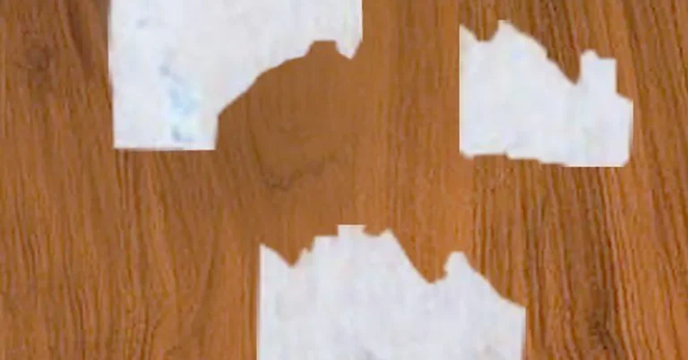 torn sticker label residue peeling off a wood laminate surface