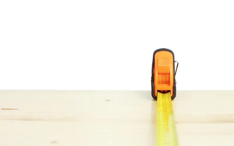 Tape measure extended across a pine board before marking a cut line Tape measure extended across a pine board before marking a cut line