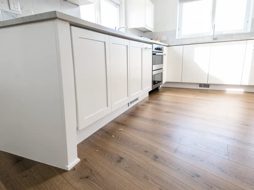 Water-resistant wood flooring installed in a modern kitchen near the sink and island cabinets
