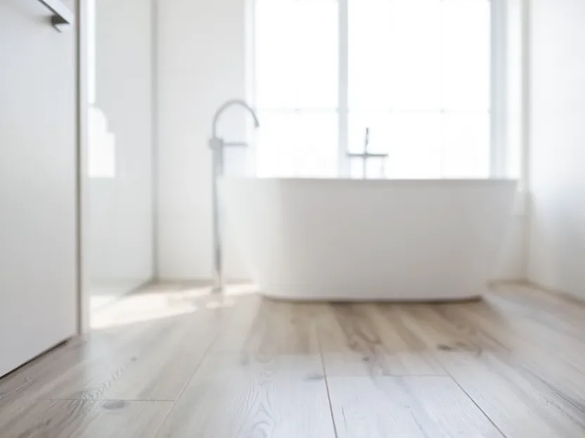 Water-resistant wood-look flooring in a bright modern bathroom with a freestanding tub