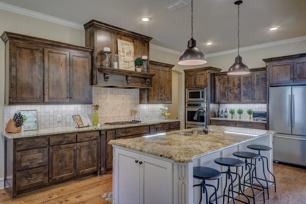 Dark stained wood cabinets above a lighter wood floor in a large kitchen