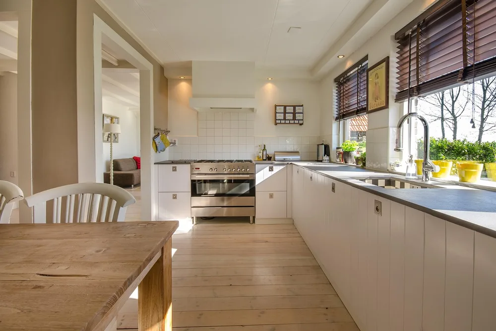White painted kitchen cabinets with a light wide-plank wood floor