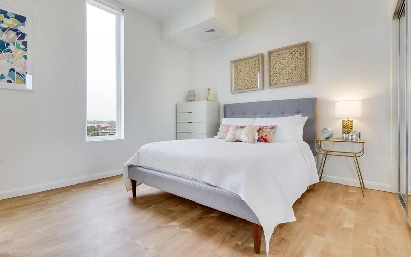 White dresser standing against a bedroom wall beside a bed White dresser standing against a bedroom wall beside a bed