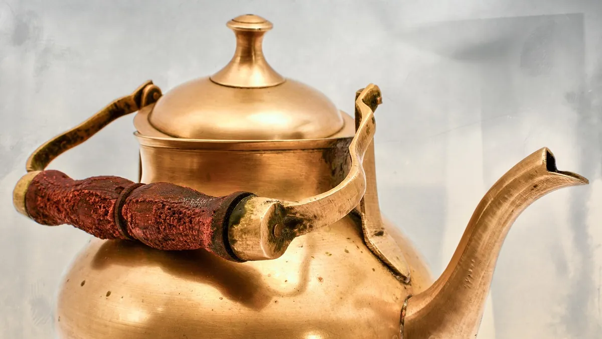 Brass kettle with a wooden handle on its bail