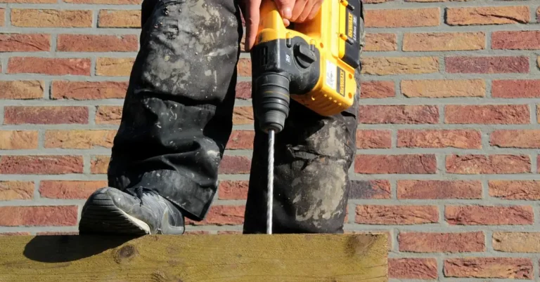 Carpenter drilling into a concrete ceiling with a standard rotary drill and masonry bit