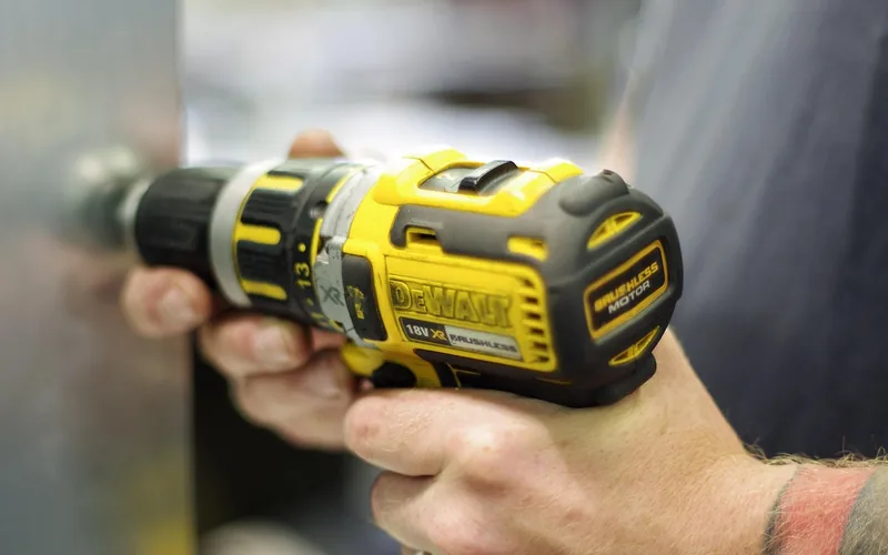 woodworker gripping a cordless drill with both hands to keep it steady while drilling woodworker gripping a cordless drill with both hands to keep it steady while drilling