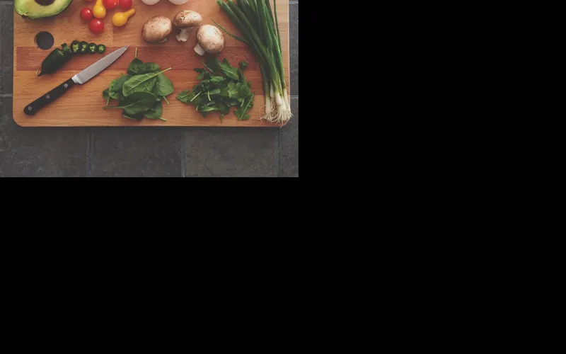 Glued-up edge-grain wood cutting board with knife and vegetables Glued-up edge-grain wood cutting board with knife and vegetables