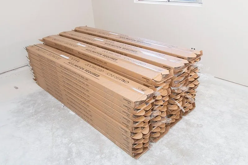 Boxed engineered hardwood flooring planks stacked in a room during acclimation