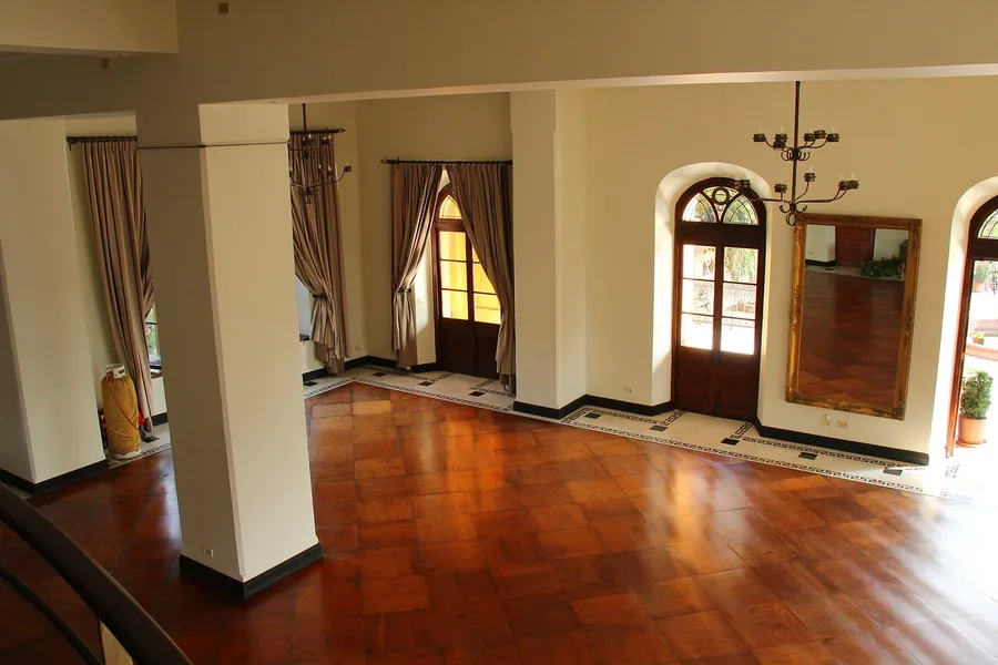 Glossy amber-toned parquet hardwood floor in a large room with tall windows