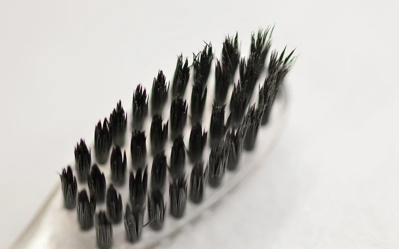 dense boar bristles showing trapped hair and product buildup that should be removed before washing