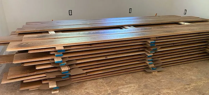 Hardwood flooring planks stacked flat with spacers during acclimation before installation