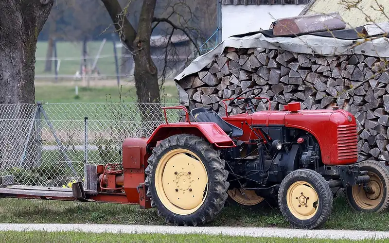 Tractor PTO-driven hydraulic log splitter positioned next to split firewood