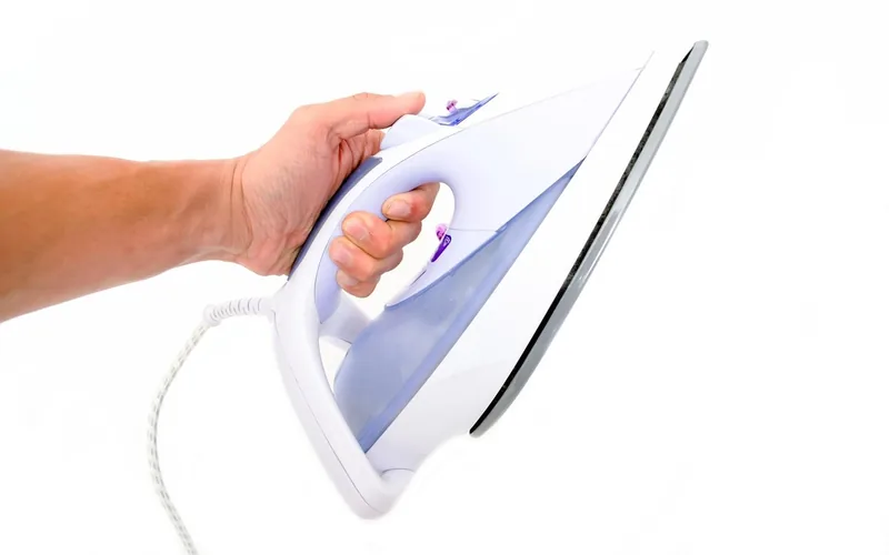 iron low heat setting wood water stain hand holding a clothes iron set to a low dry heat setting, no steam