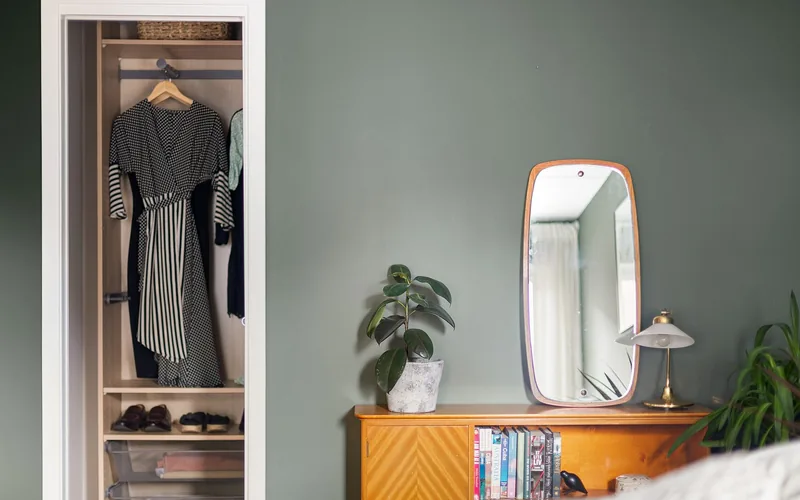 Wooden cabinet and wall mirror against a painted bedroom wall Wooden cabinet and wall mirror against a painted bedroom wall