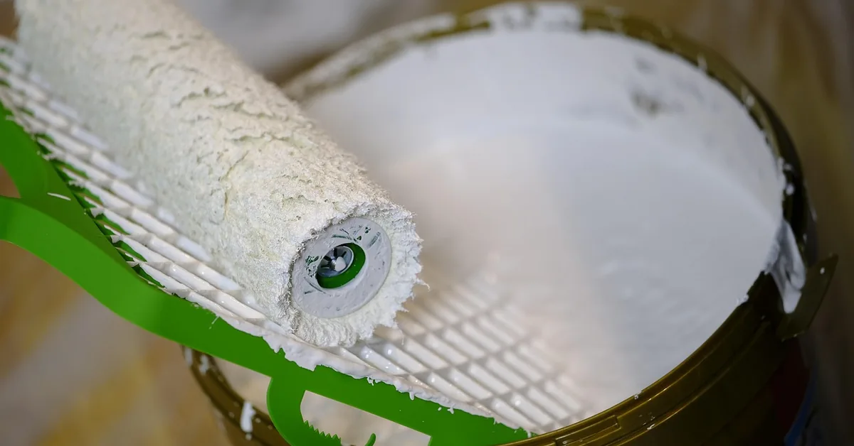paint roller resting in a can of white paint during a renovation project