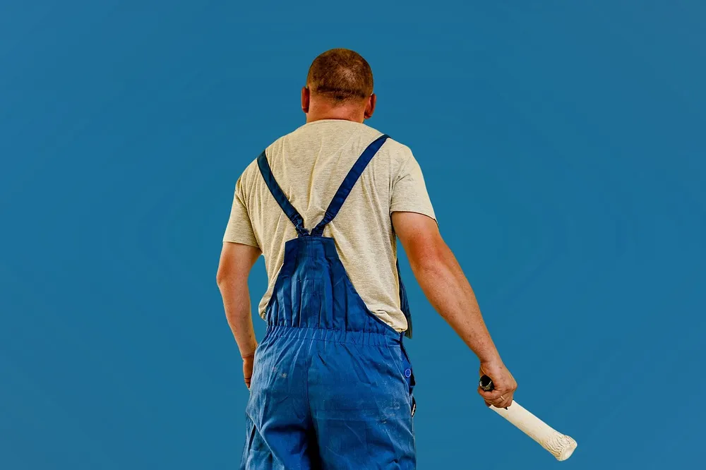 Painter holding an extendable paint roller used for exterior house painting