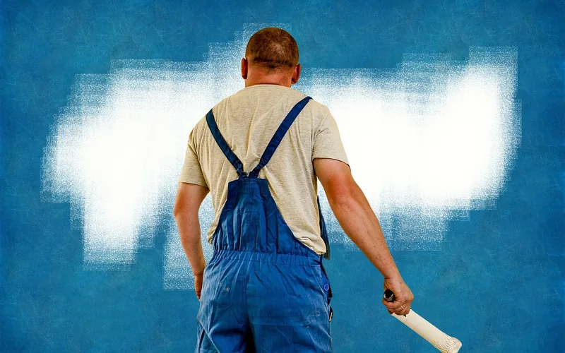 painter rolling white paint onto a prepared wall