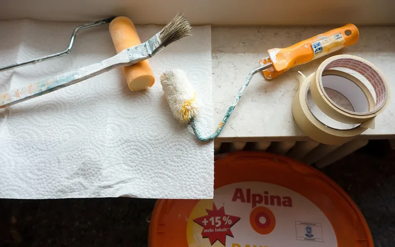 Close-up of a paint roller and painter's tape used to mask a wall edge before painting Close-up of a paint roller and painter's tape used to mask a wall edge before painting