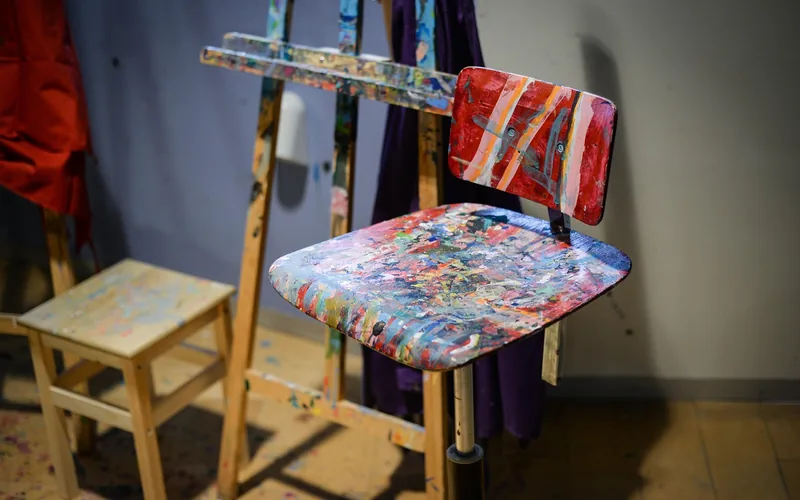 painter applying no-sand furniture paint to a wooden chair in a home workshop