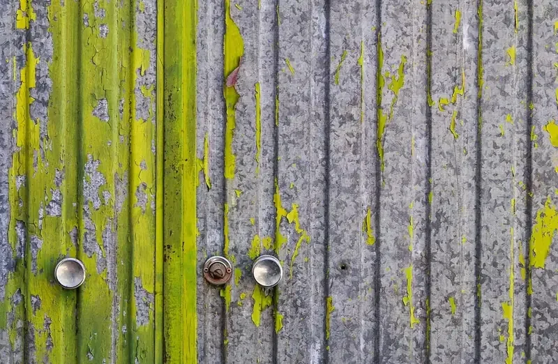 Green paint peeling off a galvanized steel door