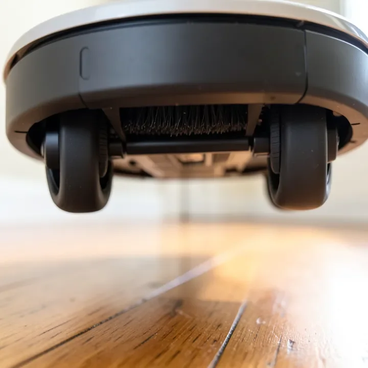 Underside of a robot vacuum showing soft rubber wheels and brush roll safe for hardwood