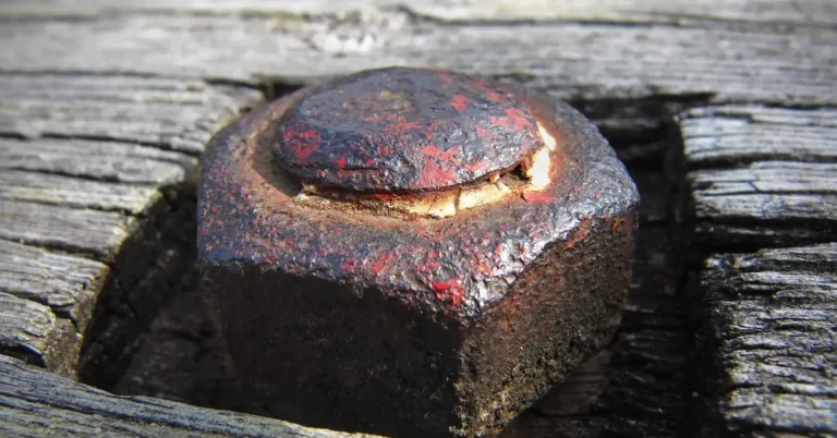 heavily rusted bolt head sitting in a decking board's screw recess