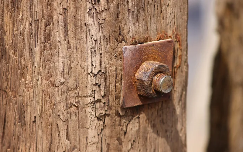 Rusted bolt and square washer plate on a weathered wooden post Rusted bolt and square washer plate on a weathered wooden post