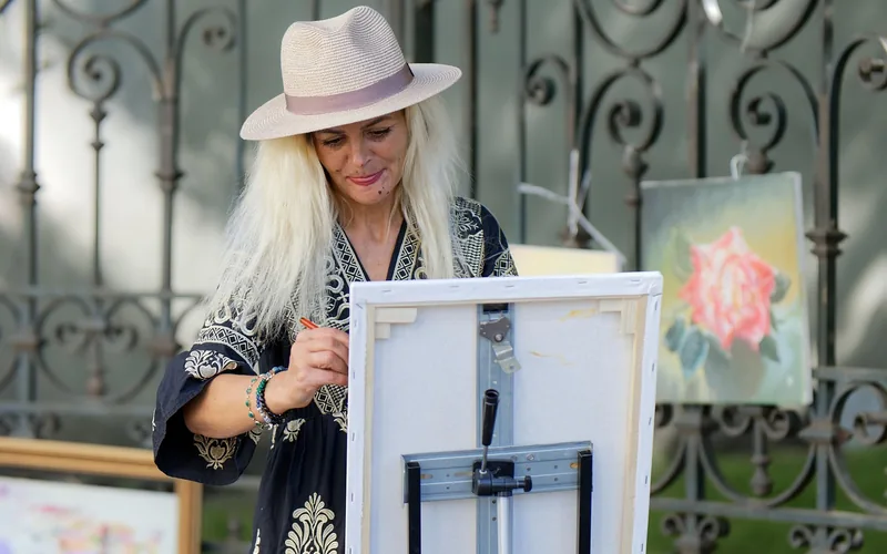 person applying wood stain to a fence panel outdoors with a paintbrush person applying wood stain to a fence panel outdoors with a paintbrush