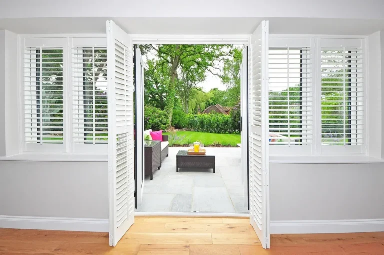 White interior plantation shutters folded open beside a set of patio doors