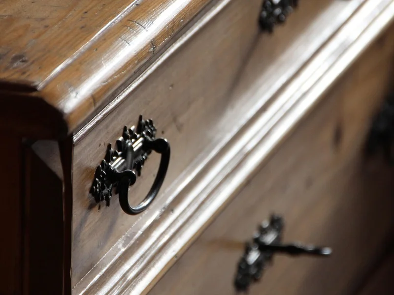 close-up of a finished wood dresser with drawer pulls and aged varnish