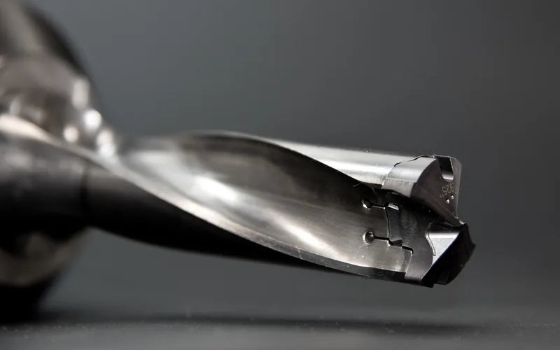 Close-up of a metal drill bit tip, showing the cutting edges and flutes ground for metal work