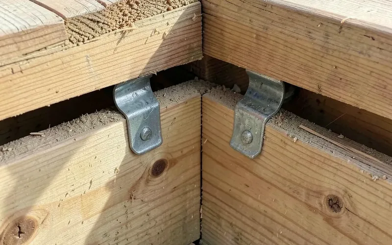 deck joist framing with metal joist hangers at a corner where two deck sections meet