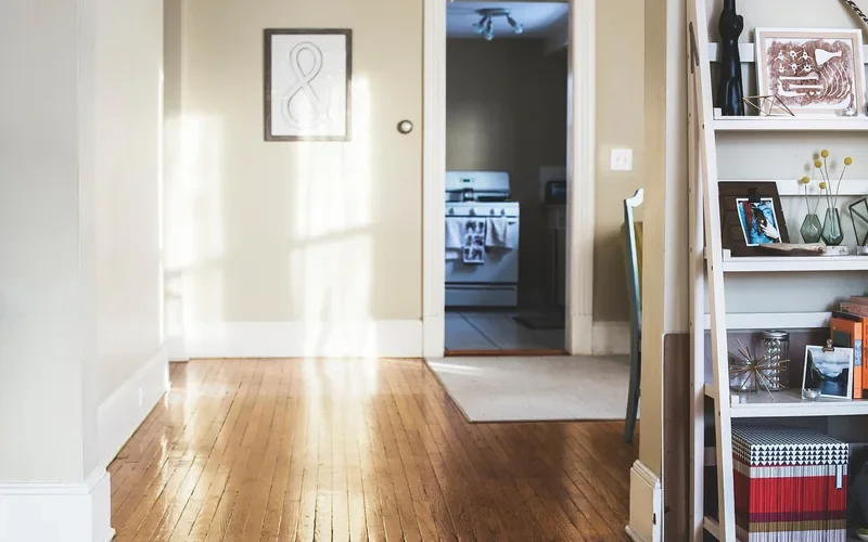 Hallway with white painted baseboards and door trim beside a glossy hardwood floor