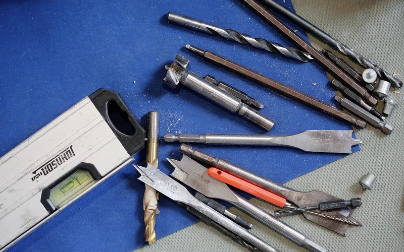 assorted hole saw and drill bit kit laid out on a workbench