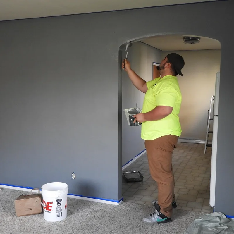 Painter using a roller to apply paint to an interior wall