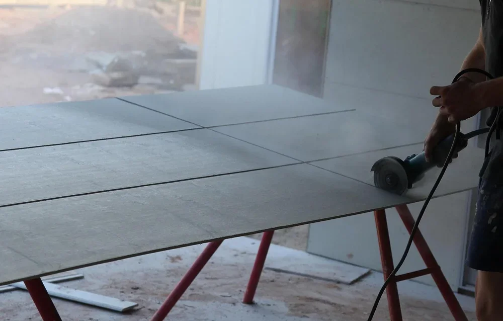 sheet panel laid across a pair of sawhorses while a worker cuts it