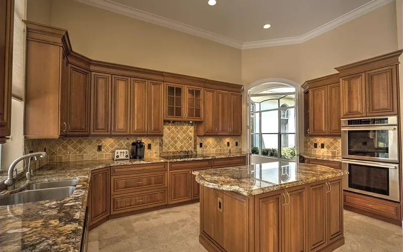 Stained wood kitchen cabinets with crown molding and a granite island