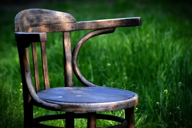 Weathered wooden armchair with a worn finish on the arms and seat edge