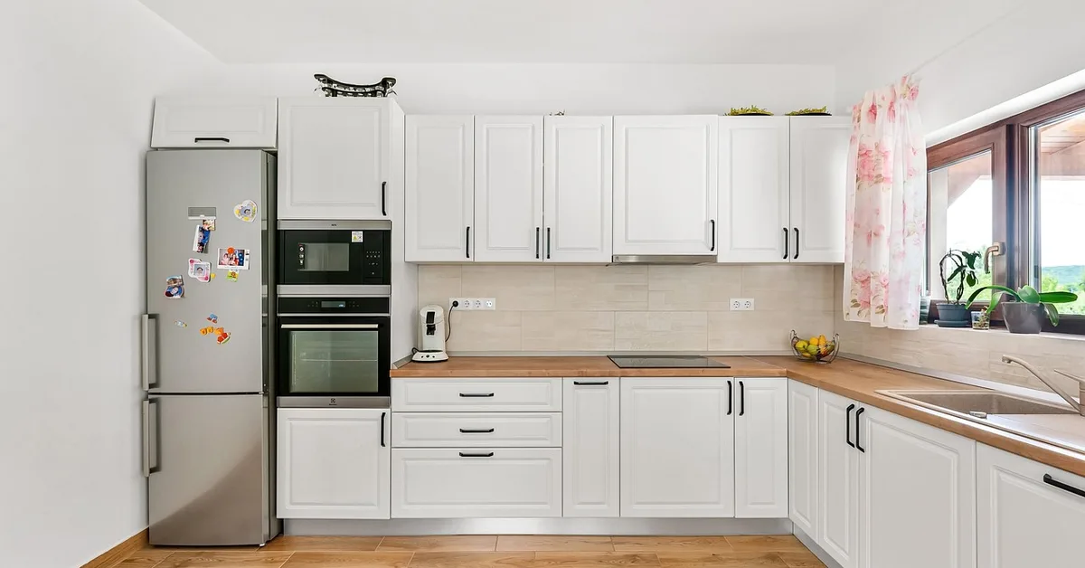 White painted kitchen cabinets with wood countertop in a clean kitchen