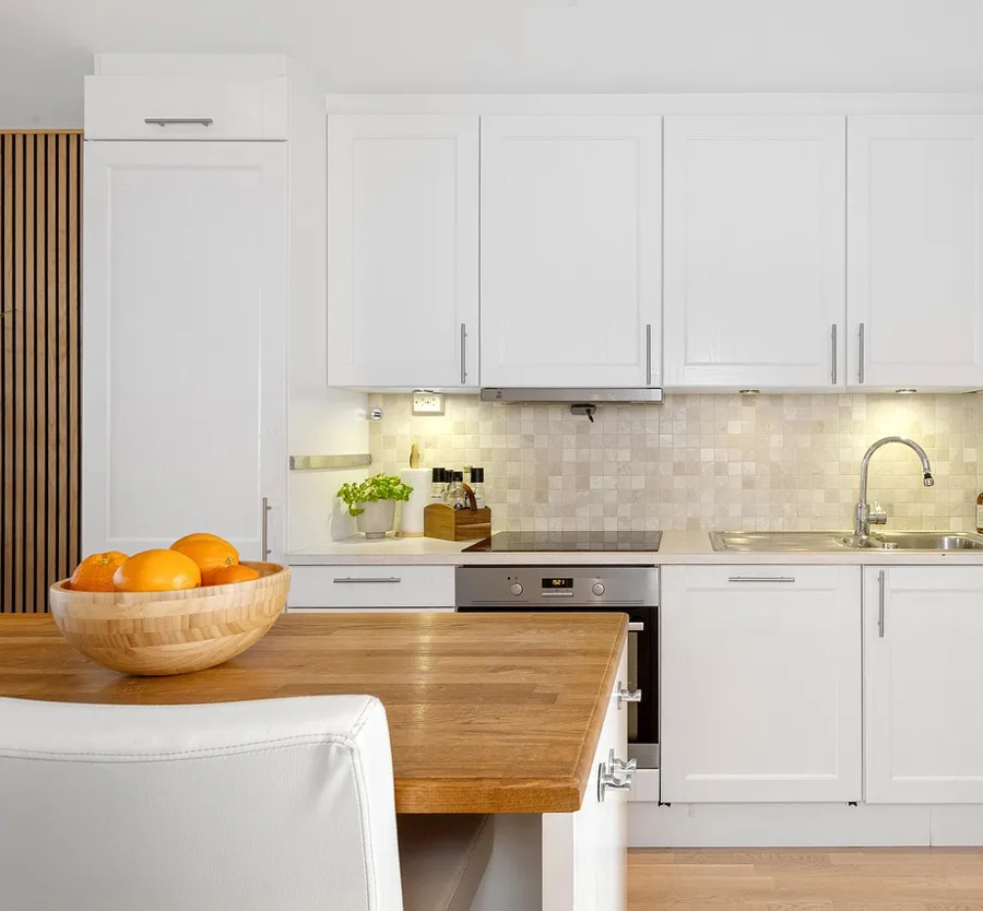 White shaker-style painted kitchen cabinets above a sink and stove