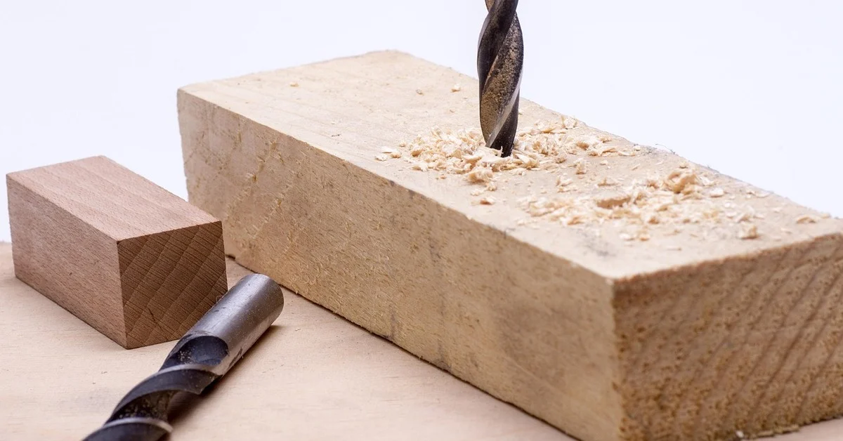 drill bit boring a hole into a wooden block with wood shavings