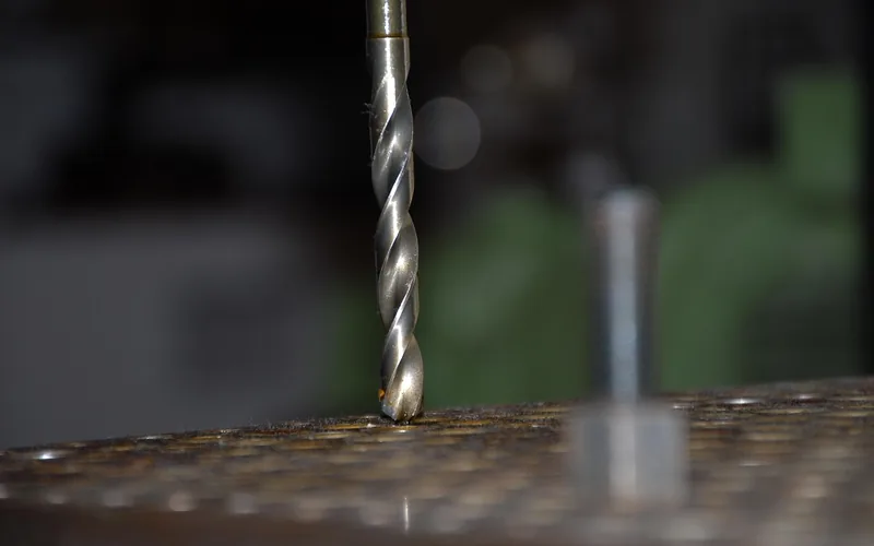 close-up of a drill bit driving a screw into wood in a home workshop