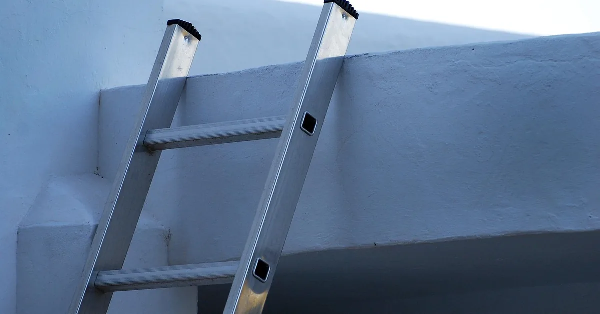 Aluminum ladder leaning against a painted wall