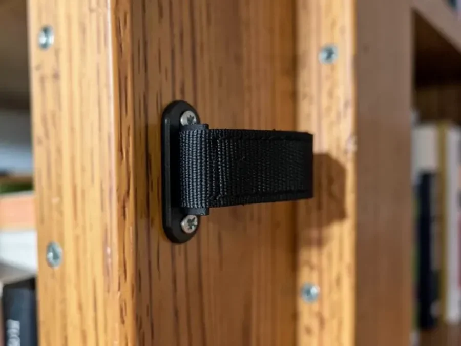 Anti-tip strap bracket screwed into a wall stud behind a bookshelf
