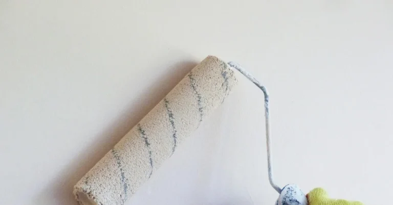 Paint roller rolling a coat of white paint onto an interior wall