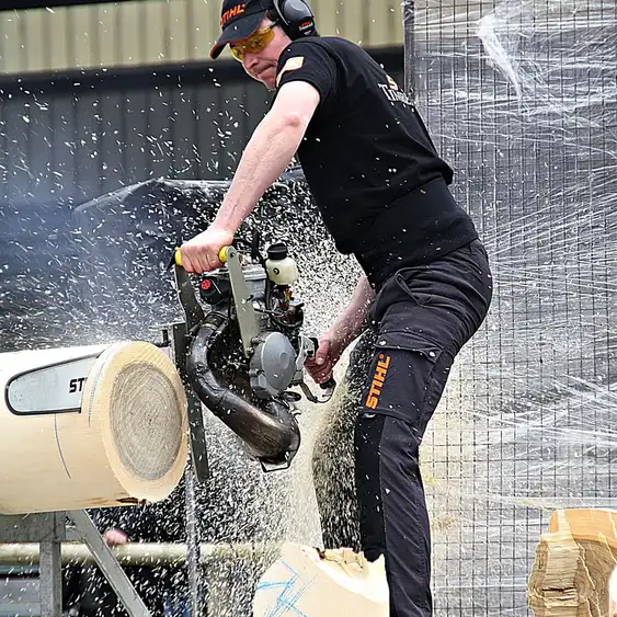 Chainsaw cutting through a log with wood chips flying