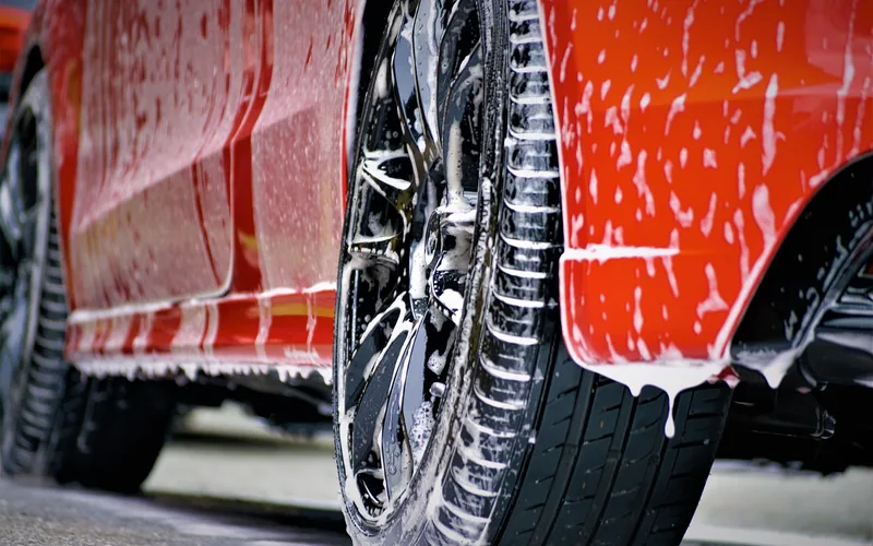 spray bottle and microfiber cloth applying cleaning solution to a car panel