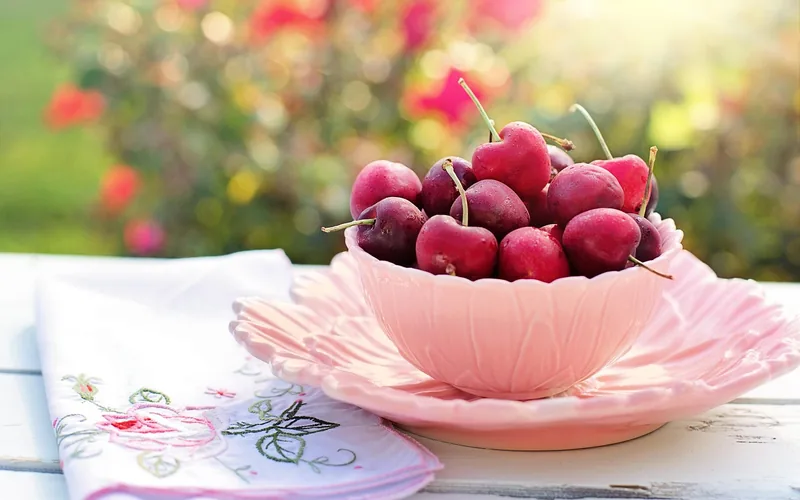 Fresh red cherries in a bowl with pits being removed for planting