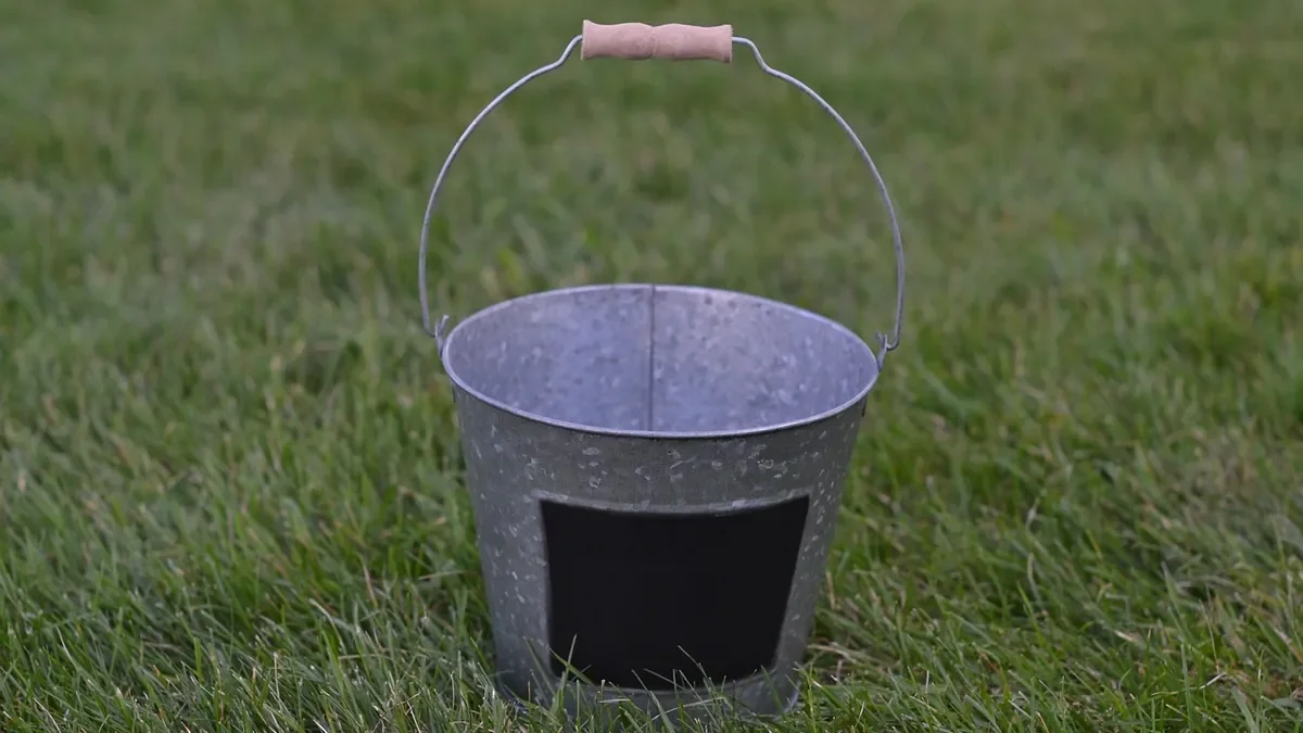 galvanized steel bucket with a wooden handle sitting on grass